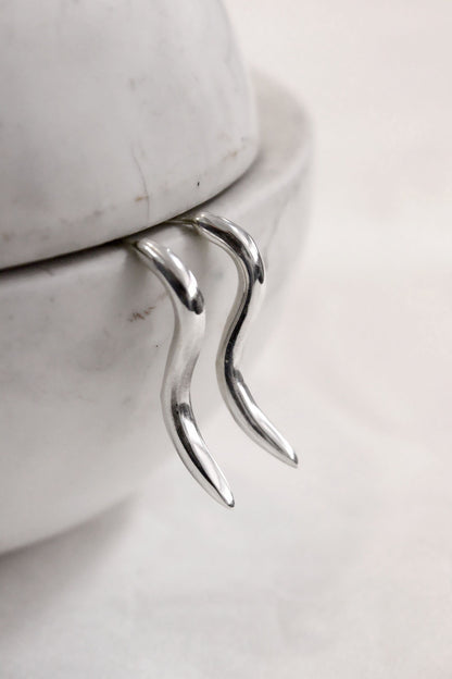 Silver pair of earrings on a marble surface