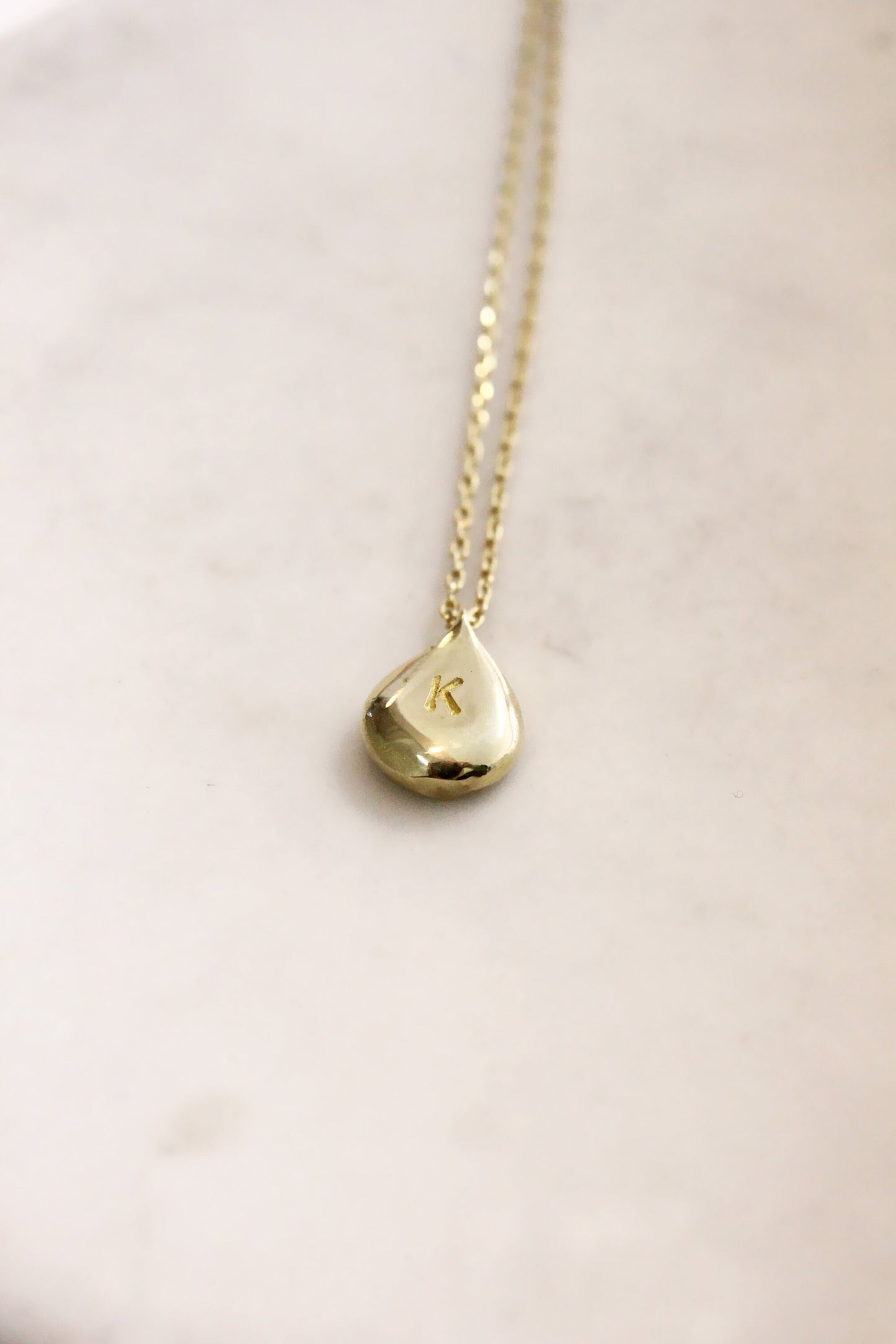 Gold necklace with a teardrop-shaped personalized initials monogram 