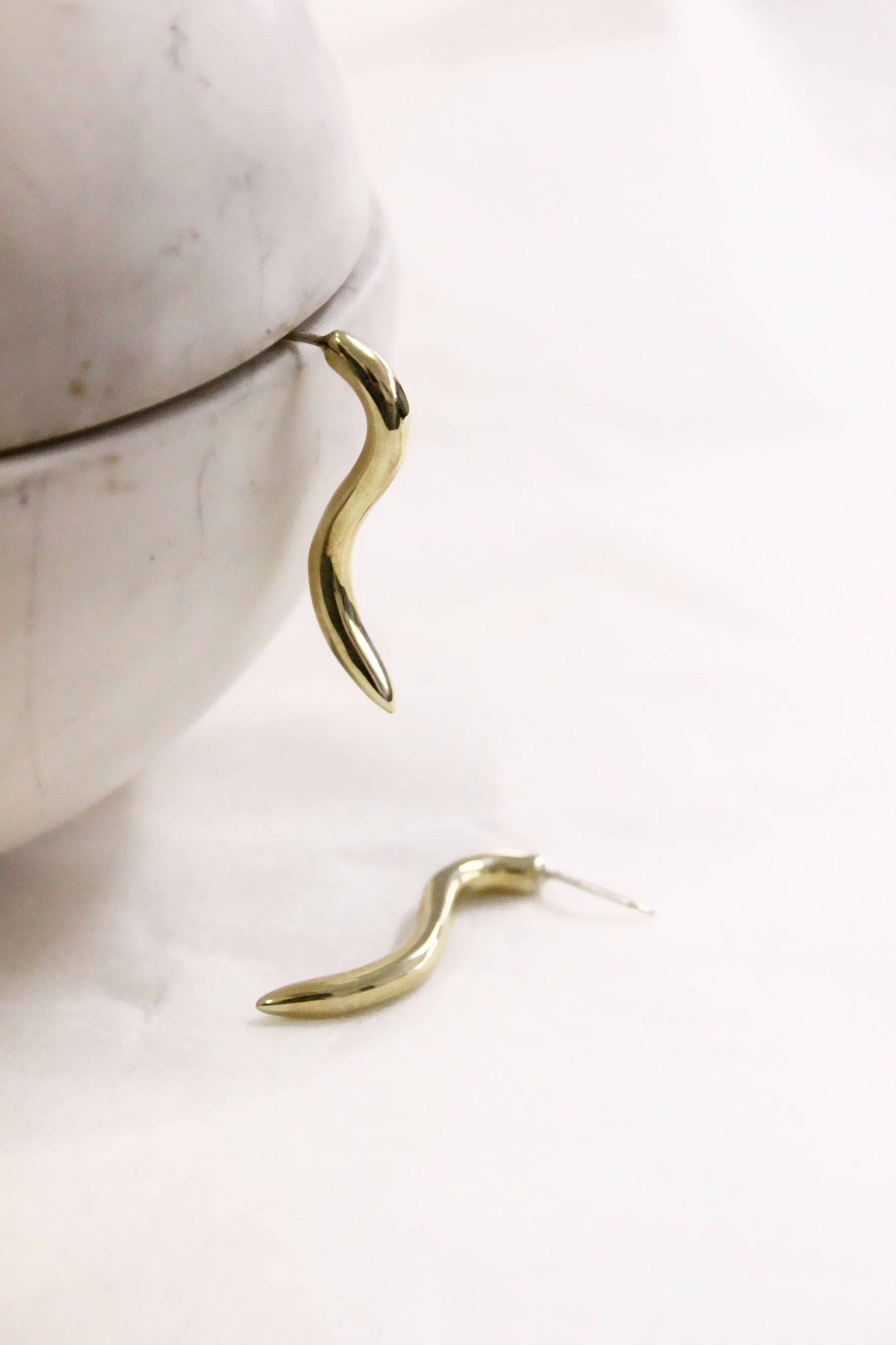 Gold earrings on a marble surface