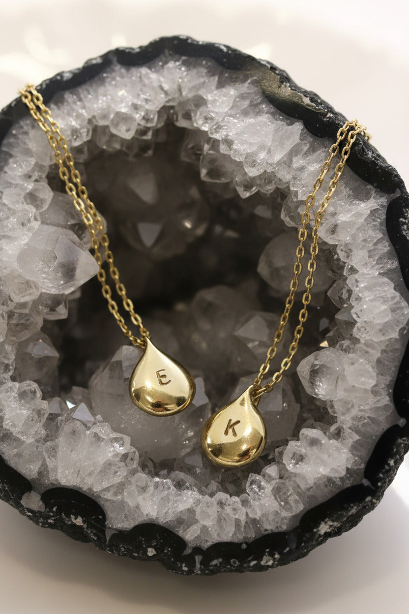 Gold teardrop pendants on a white dish