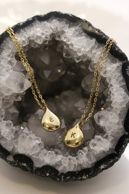 Gold teardrop pendants on a white dish