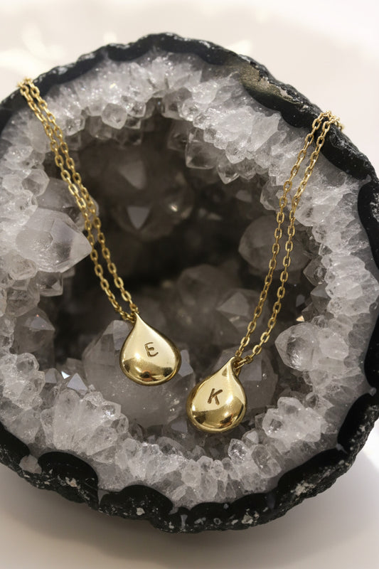 Gold teardrop pendants on a white dish