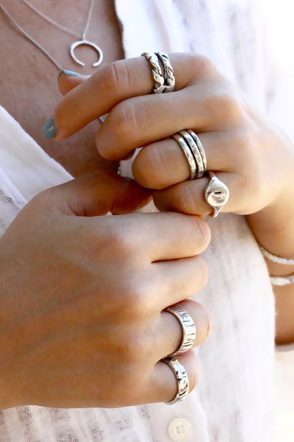 Close-up of hands wearing multiple gold rings on a light background