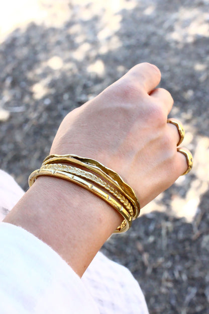 Hand wearing multiple gold bracelets