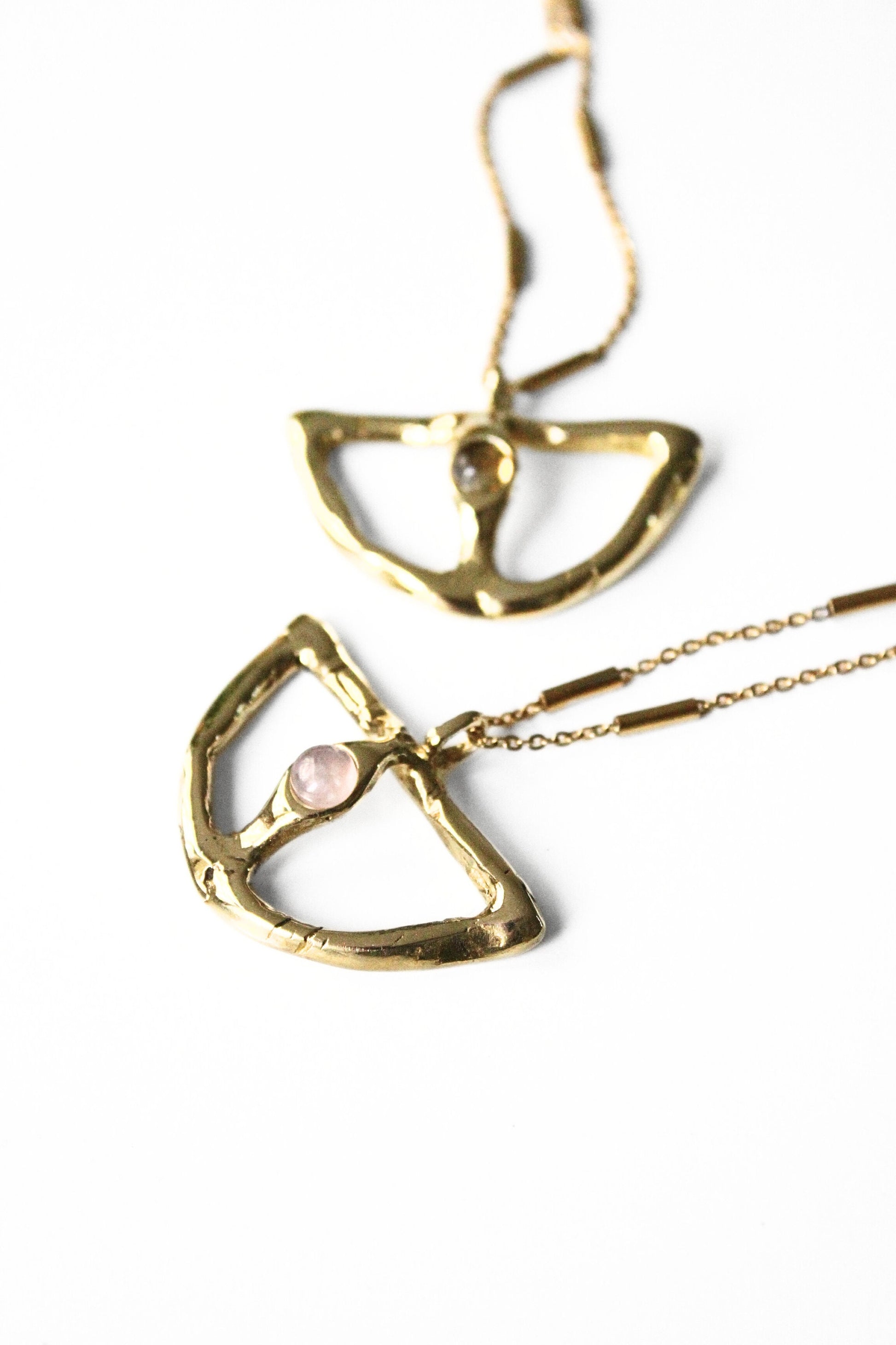 Gold necklaces with geometric pendants on a white background